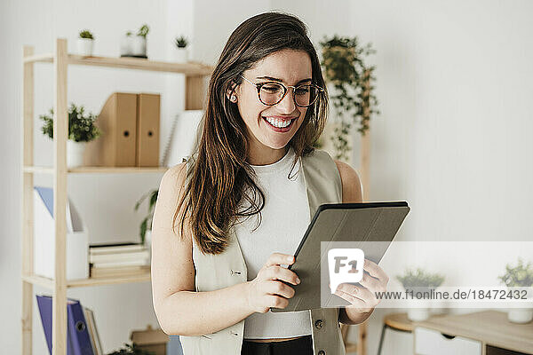 Happy businesswoman with tablet computer in office