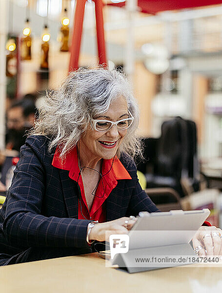 Smiling businesswoman using tablet PC in cafe