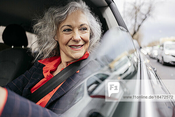 Thoughtful smiling businesswoman driving car