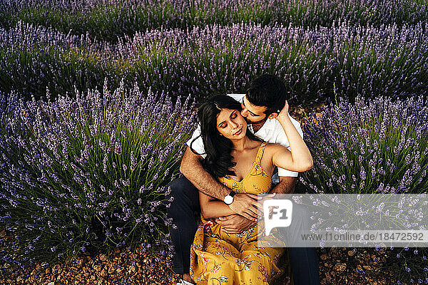 Man embracing woman sitting in lavender field