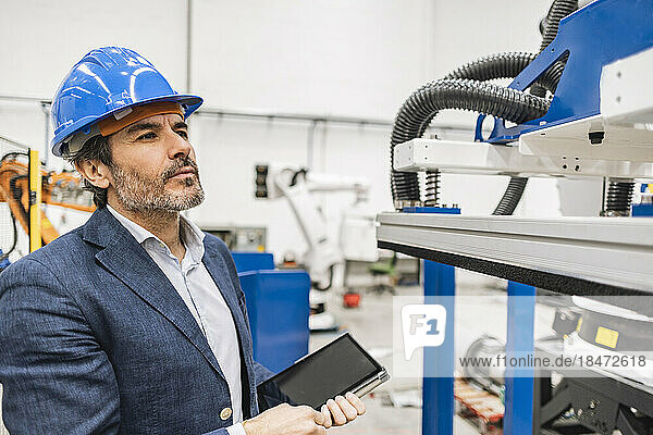 Engineer wearing hardhat examining machine parts in factory