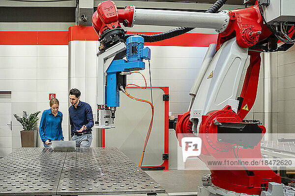 Business colleagues working on laptop in robot factory