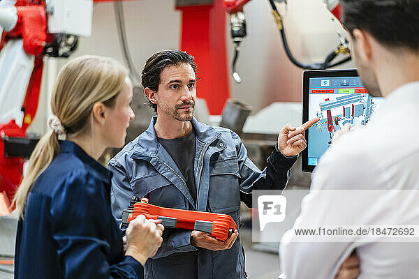 Engineer pointing and talking to colleagues in meeting at factory