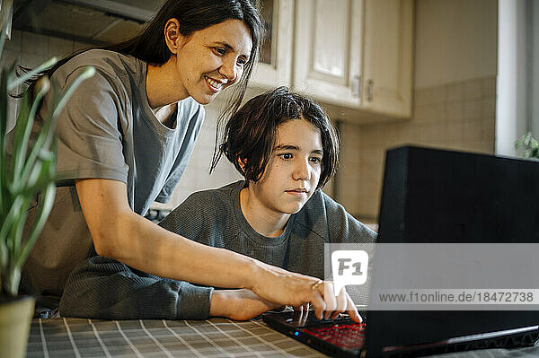 Glückliche Mutter und Sohn  die zu Hause Laptop benutzen
