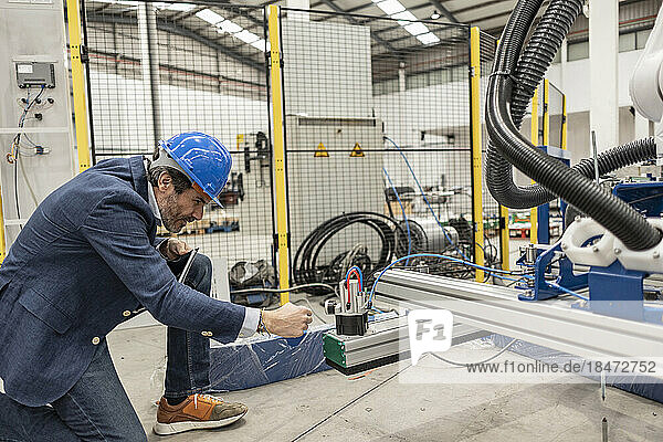 Engineer examining machine part in factory