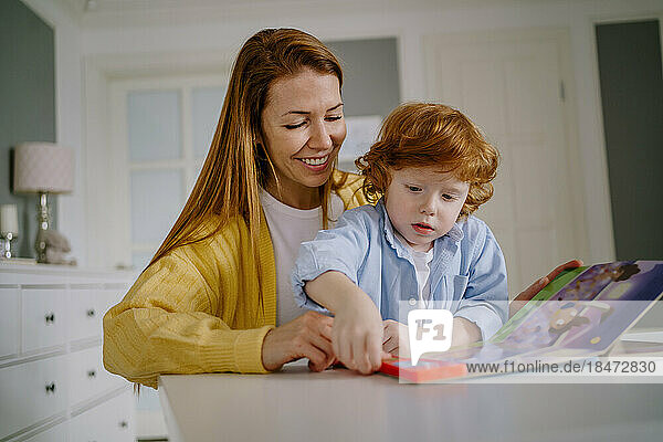 Happy woman and son reading book at home