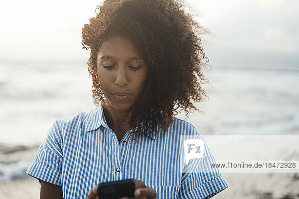 Frau benutzt Mobiltelefon am Strand