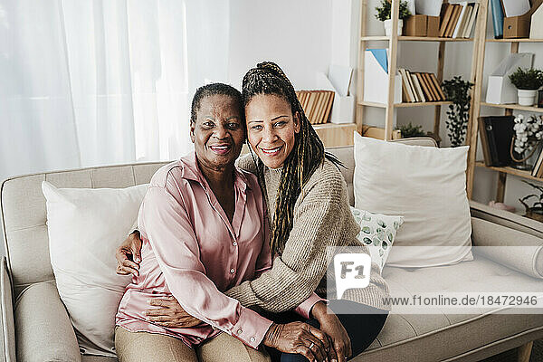 Lächelnde Mutter und Tochter sitzen zu Hause auf dem Sofa