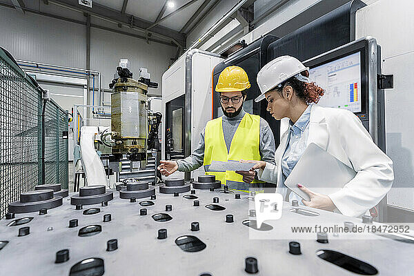 Ingenieur und Kollege analysieren Maschinenteile in der Fabrik
