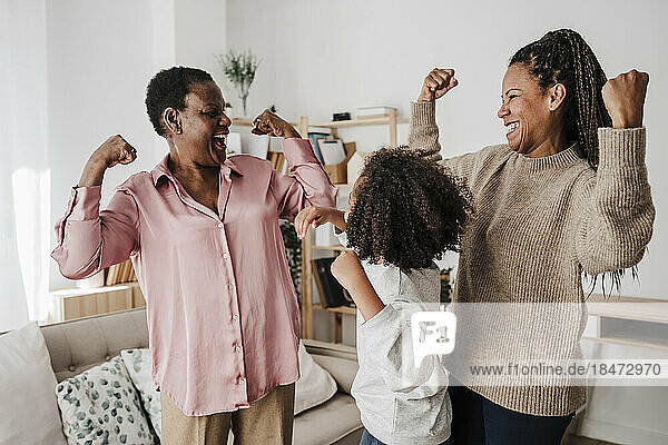 Happy family flexing muscles in living room at home