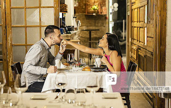Young man kissing girlfriend's hand at restaurant