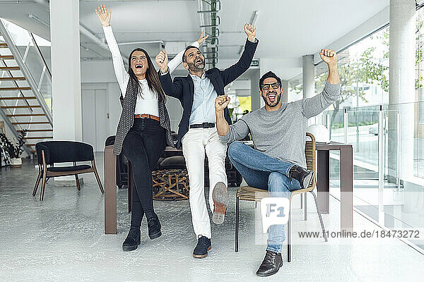 Successful businessmen and businesswoman cheering in office