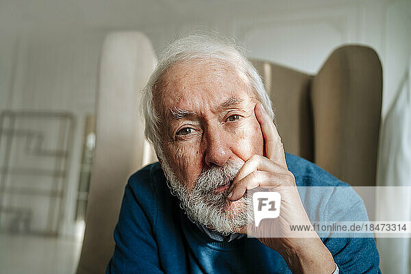Nachdenklicher älterer Mann mit grauen Haaren  der zu Hause sitzt