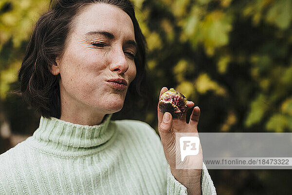 Woman with eyes closed eating fig in back yard