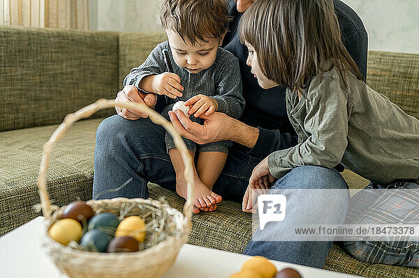 Father and sons decorating eggs for Easter at home