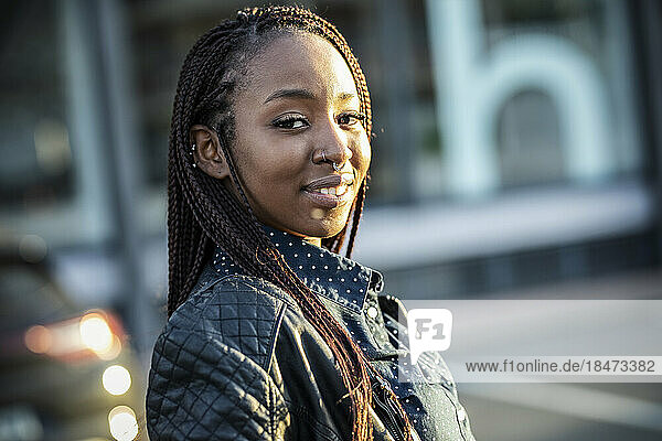 Smiling young woman with braided hair on sunny day