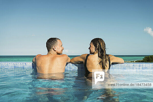 Mann schaut Freundin zu  die Urlaub im Schwimmbad verbringt
