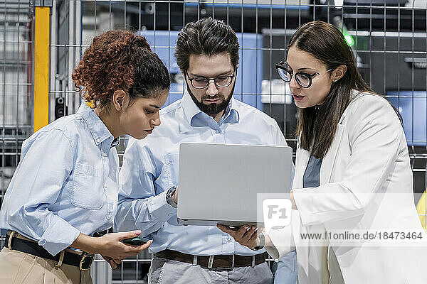Businesswoman sharing laptop with colleagues in factory