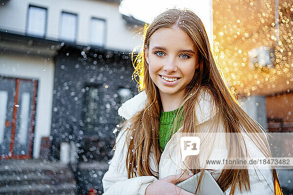 Happy teenage girl with blond hair outside home