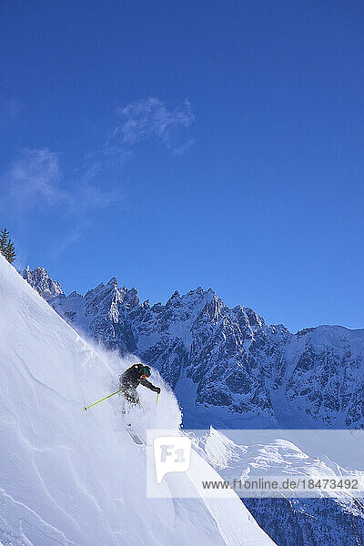 Man skiing downhill under blue sky