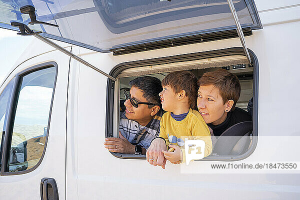 Parents with son looking through window of camper van