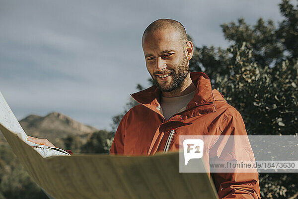 Lächelnder Mann liest Karte und steht in der Natur