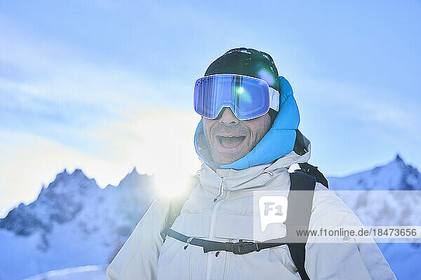 Cheerful mature man wearing ski goggles on sunny day