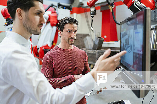 Ingenieure arbeiten am Computerbildschirm in der Roboterfabrik zusammen
