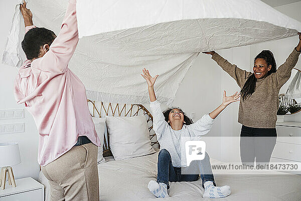 Mädchen amüsiert sich mit Mutter und Großmutter im heimischen Schlafzimmer