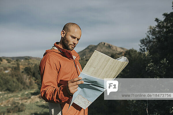 Lächelnder Mann liest Karte und steht in der Natur
