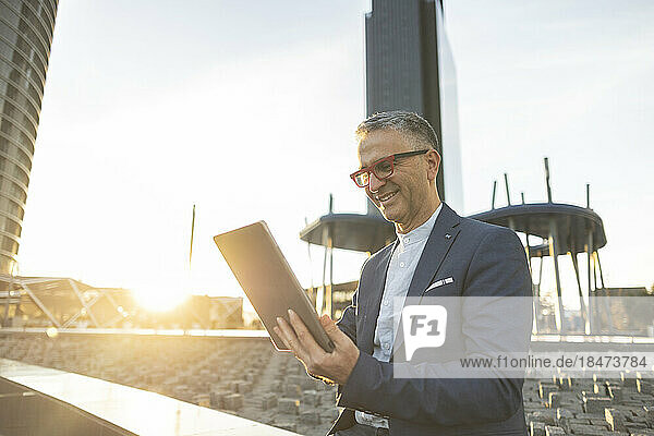Happy businessman using tablet PC on sunny day