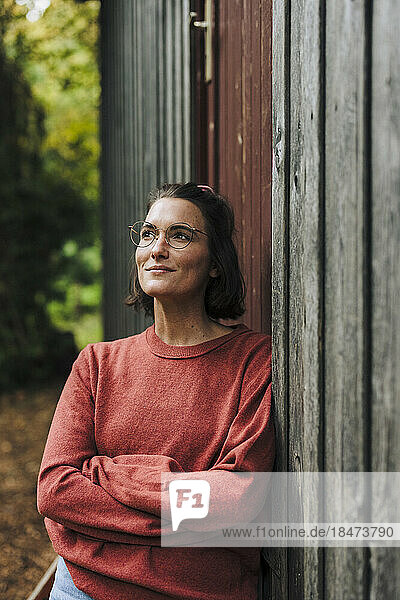 Thoughtful woman wearing eyeglasses leaning on cabin