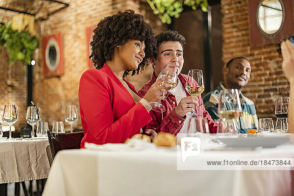 Thoughtful friends with wineglass sitting at restaurant