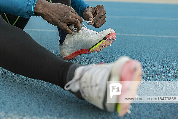 Sportler bindet Schuhe auf Sportbahn