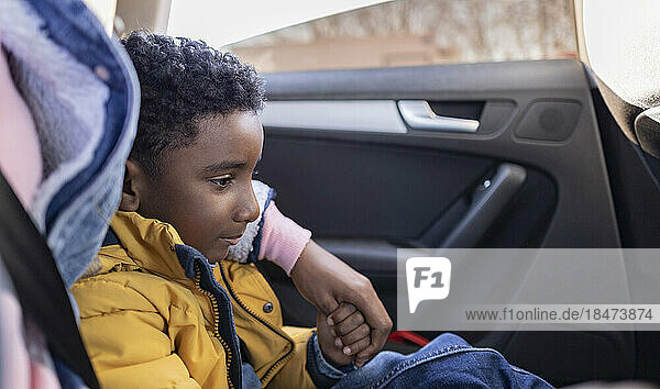 Mother sitting with arm around son in car