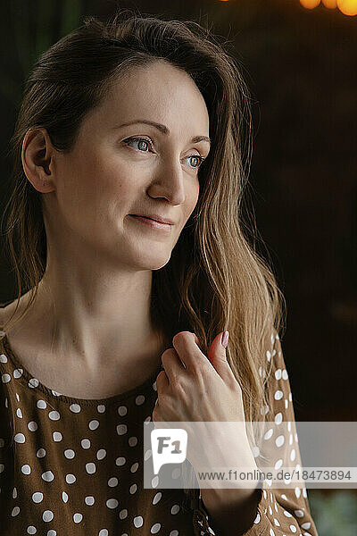 Thoughtful mature woman touching brown hair