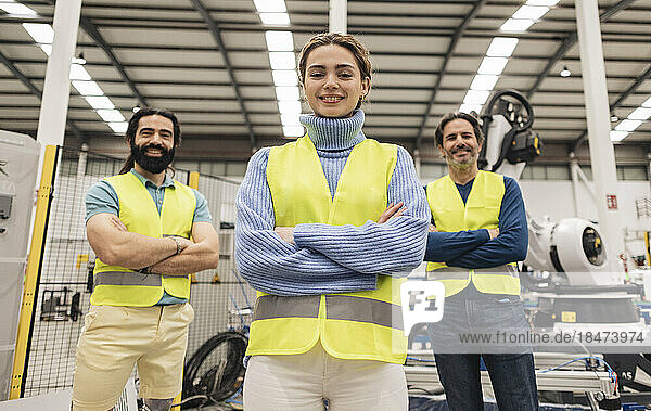 Confident engineers standing with arms crossed in robotics factory
