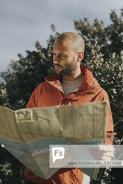 Man reading map standing in nature