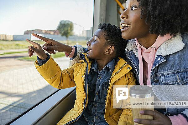 Happy mother and son pointing through window in train
