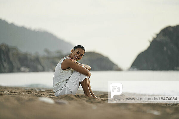 Happy woman sitting on sand at beach