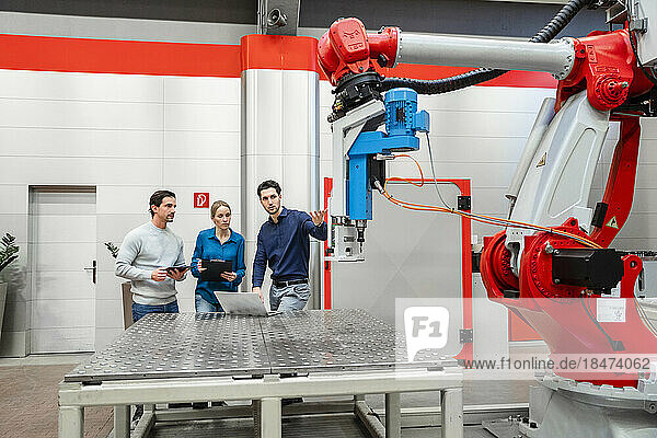 Colleagues examining robots in factory