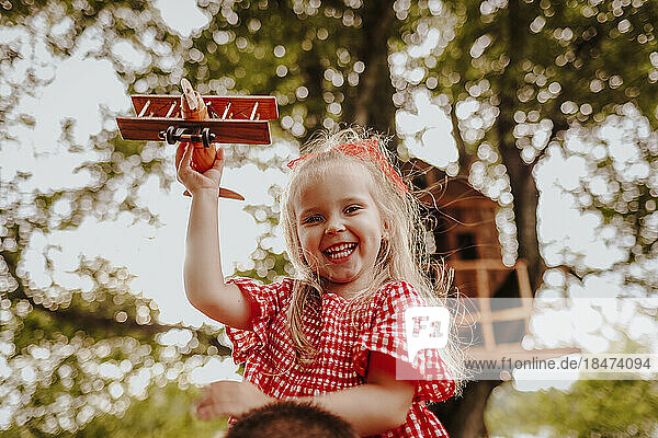 Happy girl holding wooden toy airplane