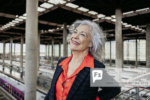 Cheerful mature businesswoman with gray hair at station