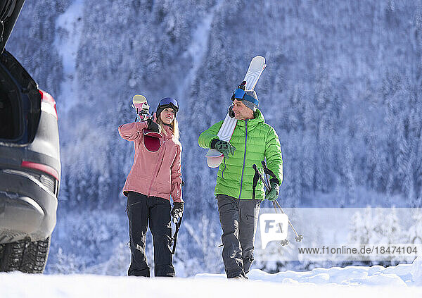 Man and woman walking with skis and poles in front of mountain