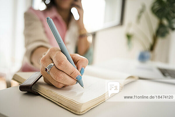 Freelancer making notes in book at home