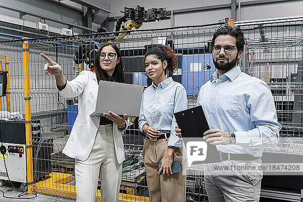 Businesswoman with laptop showing colleagues in factory