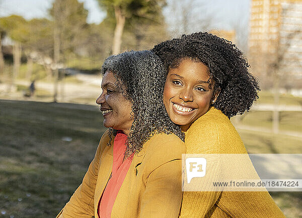 Happy young woman sitting with mother in park