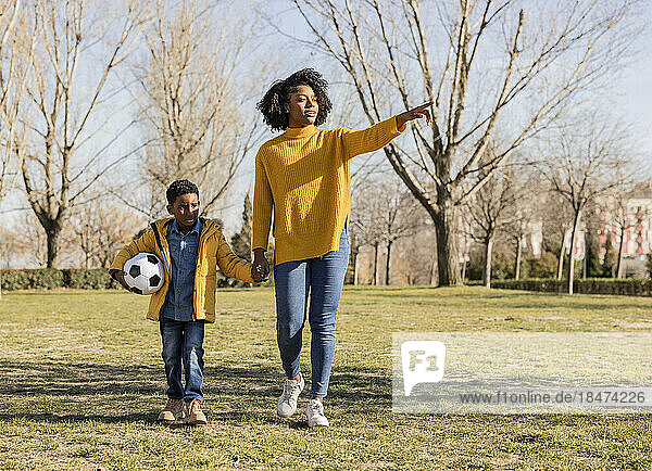 Woman walking with son pointing in park