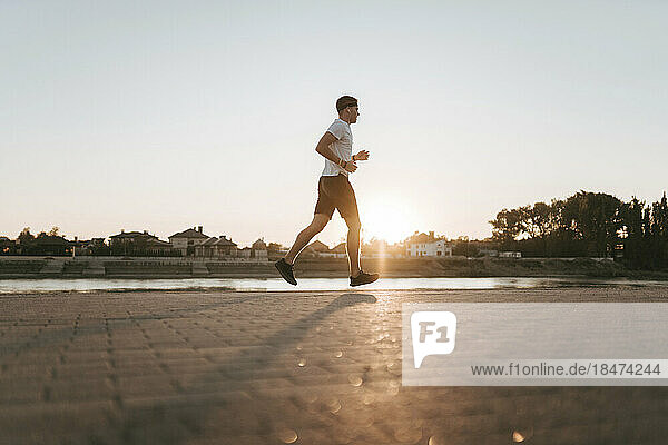 Young man running on footpath at sunset