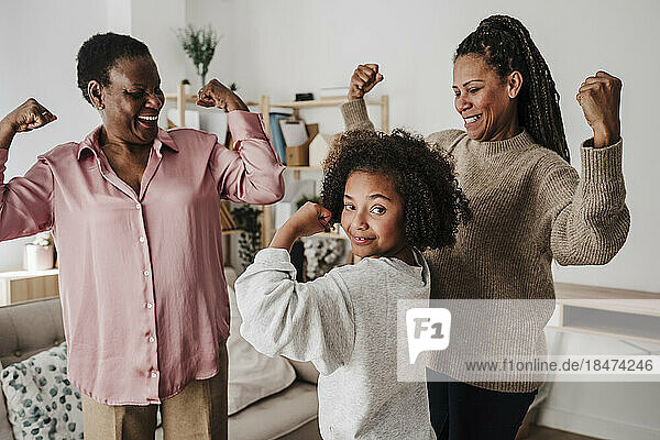 Girl flexing muscles with mother and grandmother at home